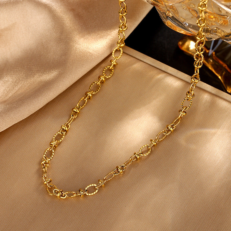 Collier Salma doré à maillons texturés présenté sur satin